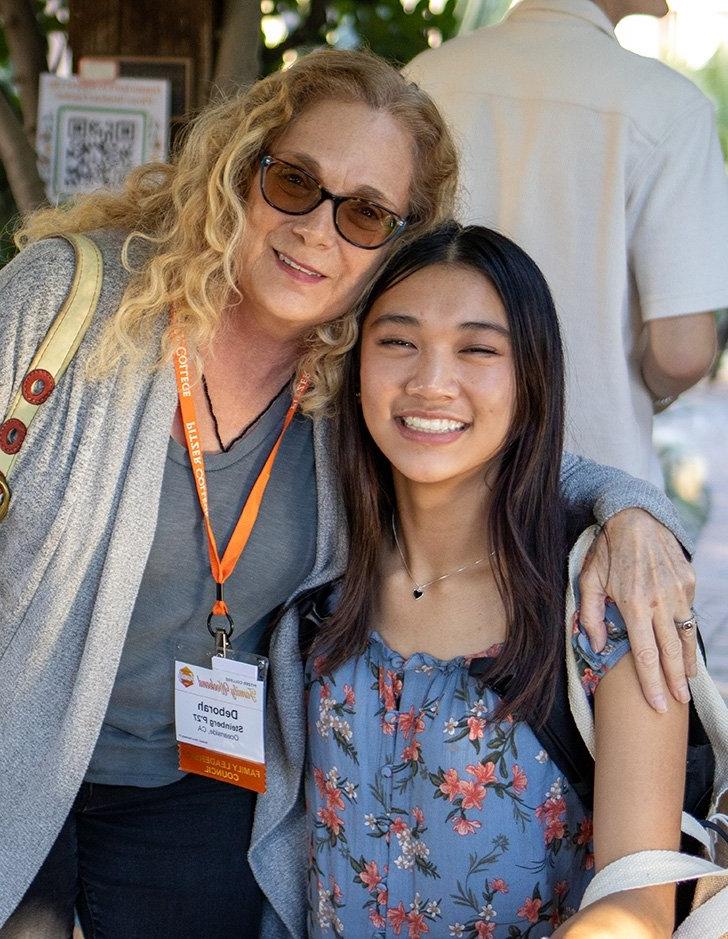 a student and their parent pose for the camera outside of the grove house